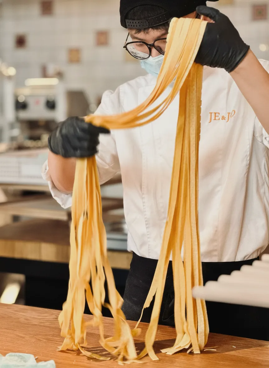 JE&JO 厨师双手提起一束刚切好的新鲜宽面